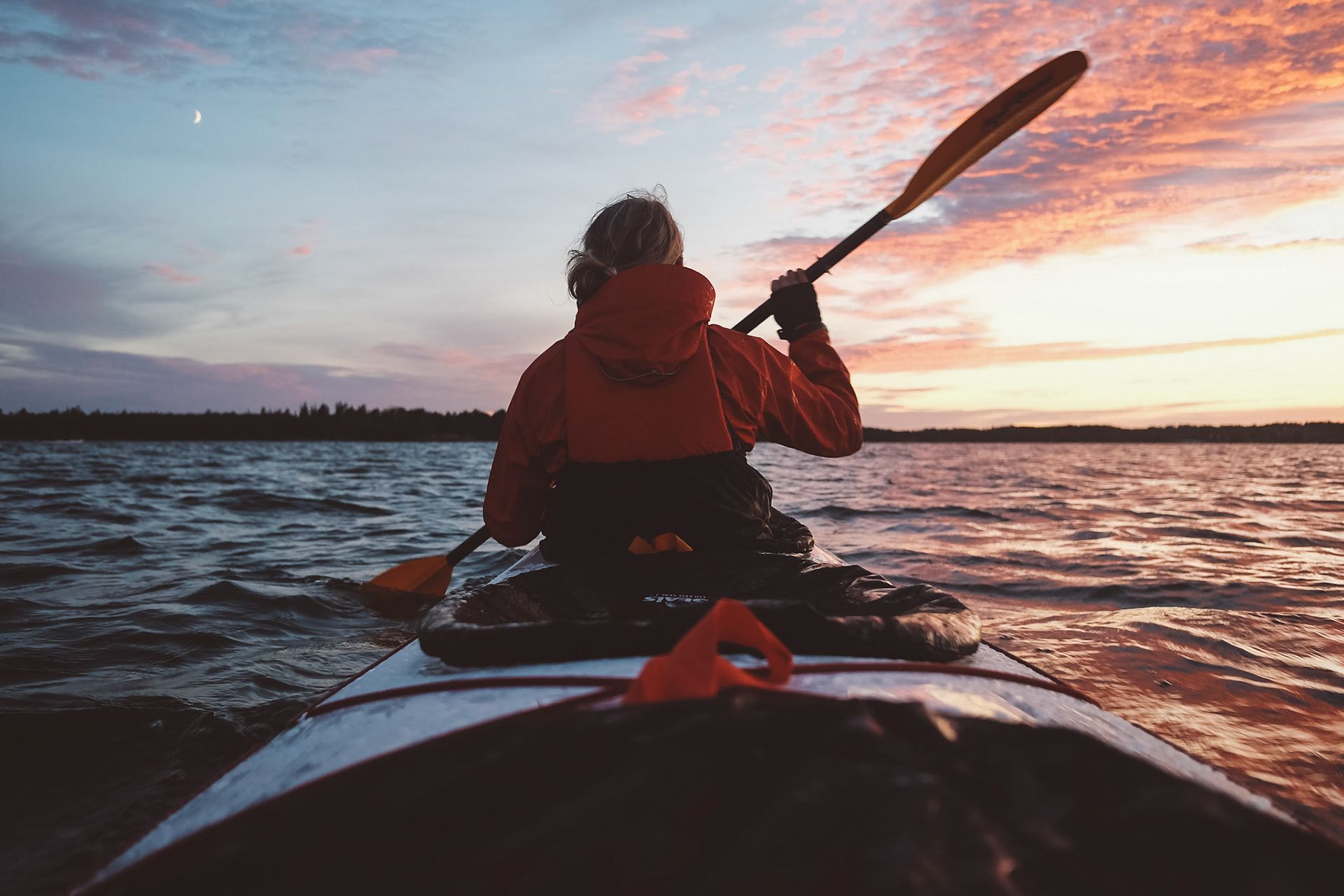 Un kayak che pagaia sull'acqua mentre il sole tramonta.