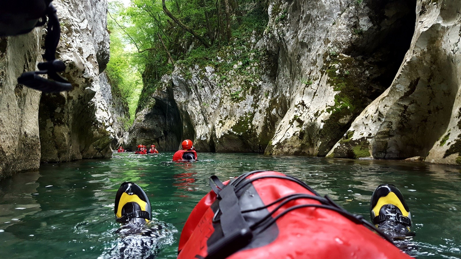 Un gruppo che fa canyoning in un fiume, dalla prospettiva ravvicinata di uno dei torrentisti.