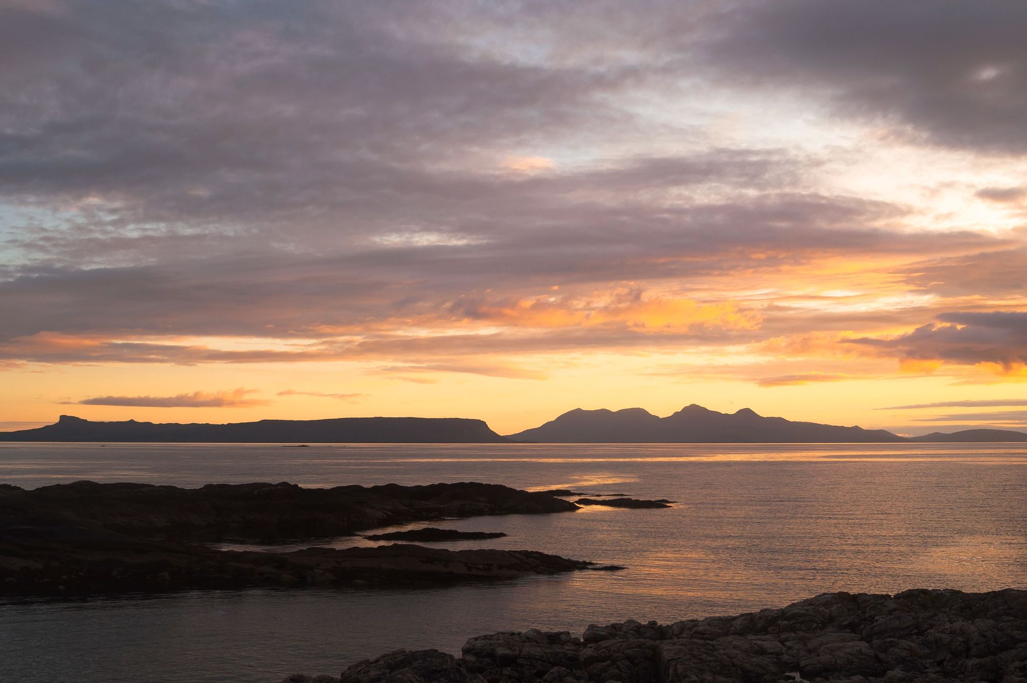 La pinna dorsale e il profilo di Eigg, a sinistra, e la cresta montuosa del Rum Cuillin, a destra, al tramonto. Foto: Getty